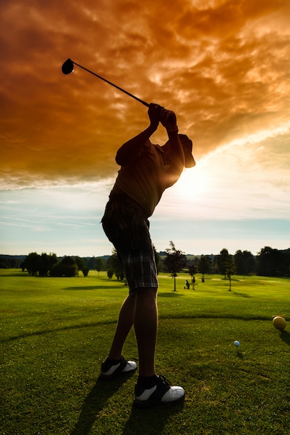 Junger Golfspieler auf dem Kurs, der Golfschwingen tut