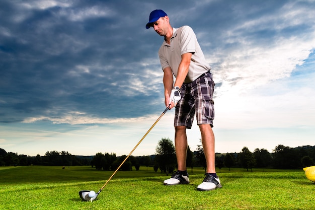 Junger Golfspieler auf dem Kurs, der Golfschwingen tut