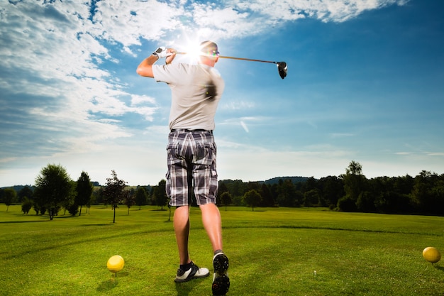 Junger Golfspieler auf dem Kurs, der Golfschwingen tut