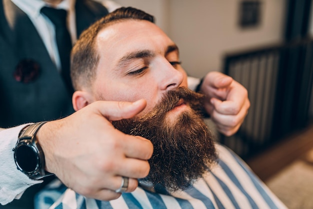 Junger gut aussehender Hipster-Mann, der Friseursalon besucht. Trendiges und stylisches Bartstyling und Schnitt.