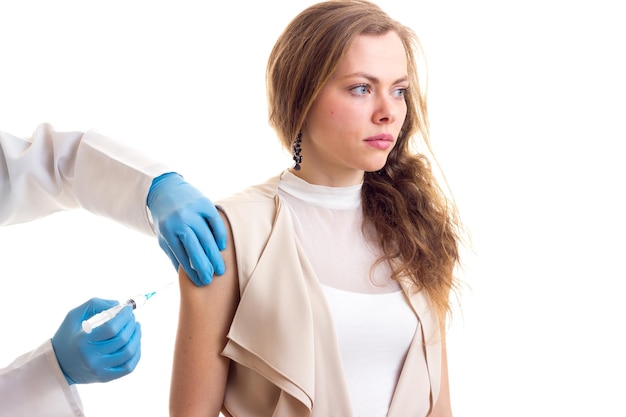 Junger gutaussehender Arzt im weißen Kleid mit Stethoskop, der einer jungen schönen Frau eine Injektion macht