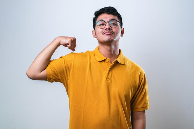 Junger gutaussehender asiatischer Mann über weißem Hintergrund in legerer Kleidung mit Armmuskeln lächelnd stolz Fitnesskonzept