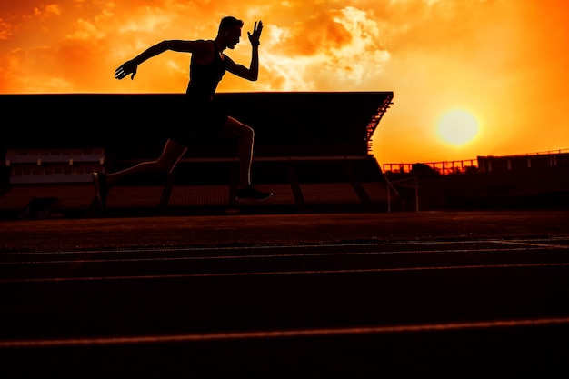 Junger gutaussehender Athlet, der bei Sonnenuntergang im Stadion läuft Foto in hoher Qualität