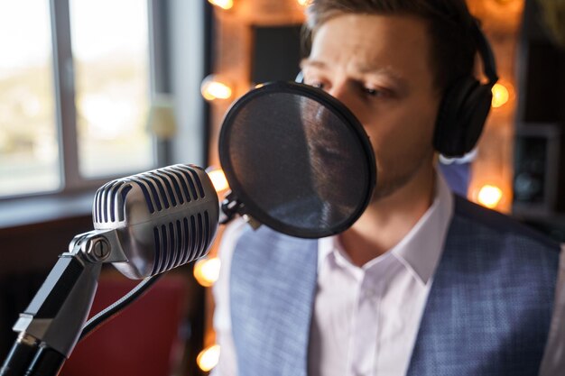 Junger gutaussehender bärtiger Mann singt in einem Heimmusikstudio in ein Mikrofon