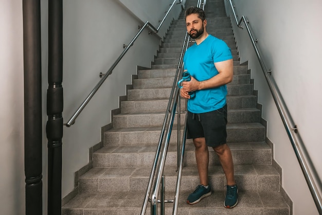 Junger gutaussehender bärtiger Sportler mit einer Flasche Wasser