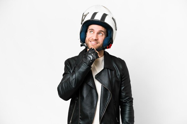 Junger gutaussehender blonder Mann mit Motorradhelm vor isoliertem weißem Hintergrund und Blick nach oben