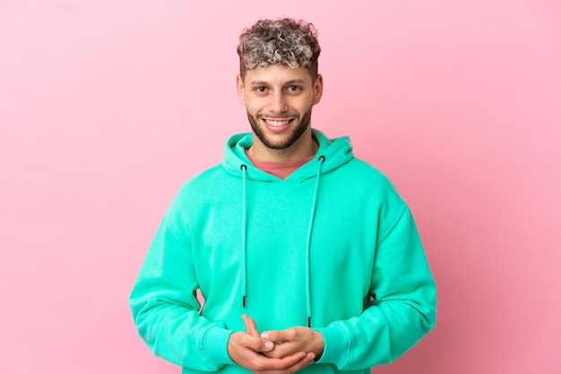 Junger gutaussehender kaukasischer Mann isoliert auf rosa Hintergrund lachend