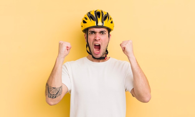 Junger gutaussehender Mann, der aggressiv mit einem Fahrradkonzept mit wütendem Ausdruck schreit