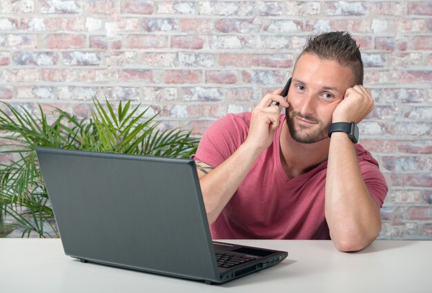 Junger gutaussehender Mann, der am Telefon im Büro spricht