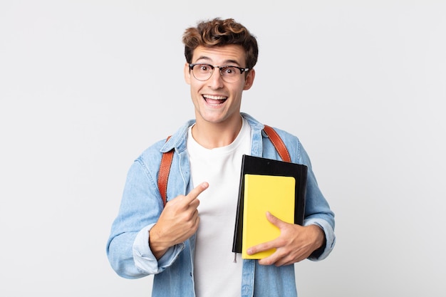 Junger gutaussehender Mann, der aufgeregt und überrascht aussieht und auf die Seite zeigt. Konzept für Universitätsstudenten