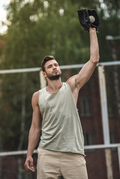 Junger gutaussehender Mann, der Baseballball auf Gericht fängt