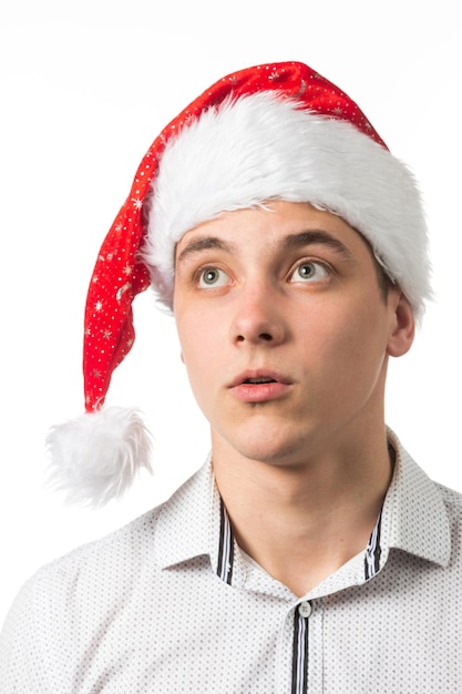 Junger gutaussehender Mann, der eine Weihnachtsmütze auf weißem Hintergrund trägt, überrascht, etwas zu zeigen und zu zeigen, das auf ihrer Hand ist