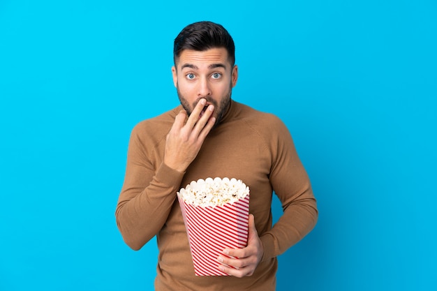 Junger gutaussehender Mann, der einen großen Eimer Popcorn hält