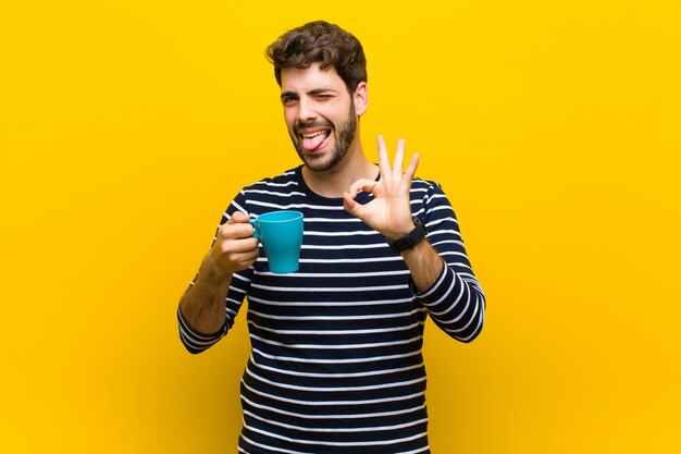 Junger gutaussehender Mann, der einen Kaffee auf Orange trinkt