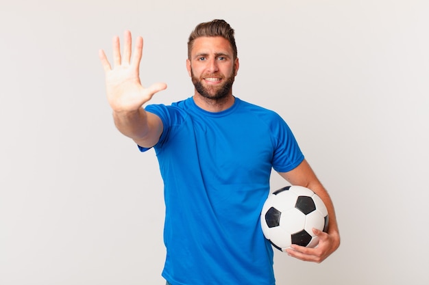 Junger gutaussehender Mann, der freundlich lächelt und aussieht und Nummer fünf zeigt. Fußballkonzept