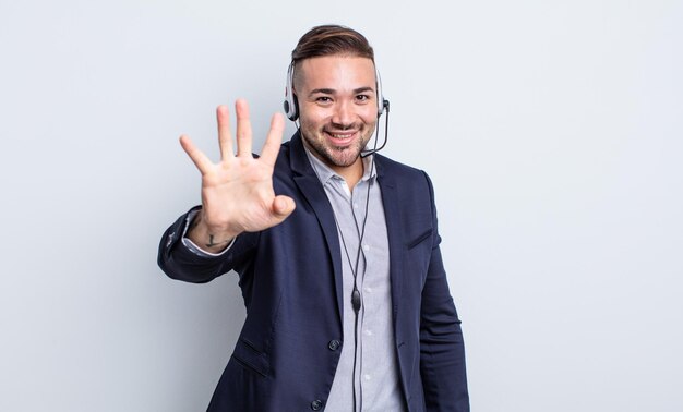 Junger gutaussehender Mann, der freundlich lächelt und aussieht und Nummer vier zeigt. Telearketer-Konzept