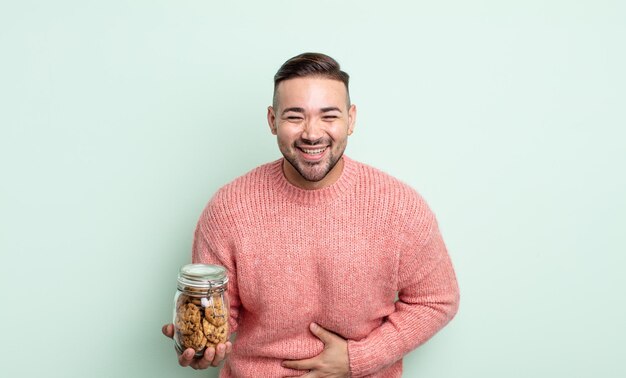 Foto junger gutaussehender mann, der laut über einen urkomischen witz lacht. keksflaschenkonzept