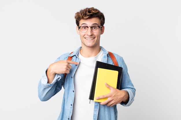 Junger gutaussehender Mann, der sich glücklich fühlt und mit einem aufgeregten auf sich selbst zeigt. Konzept für Universitätsstudenten