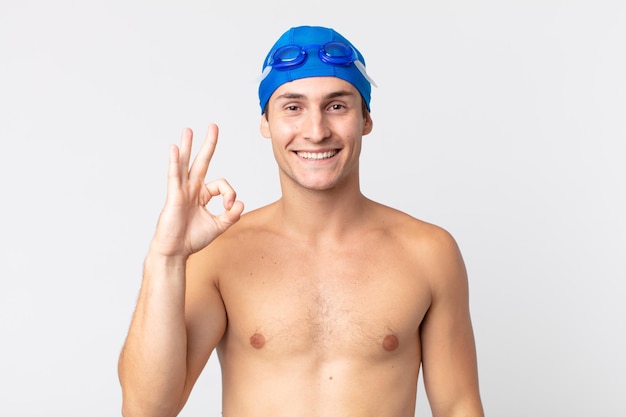 Junger gutaussehender Mann, der sich glücklich fühlt und Zustimmung mit okayer Geste zeigt. Schwimmer-Konzept