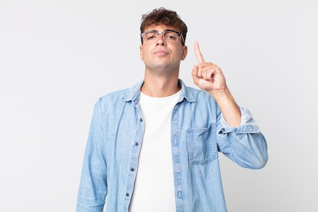 Junger gutaussehender Mann, der sich wie ein Genie fühlt, der stolz den Finger in die Luft hält, nachdem er eine großartige Idee realisiert hat, und sagt Heureka