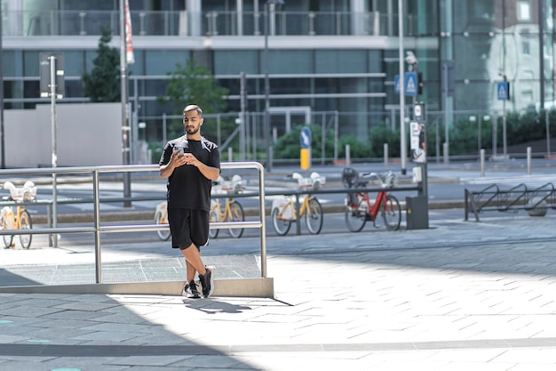 Junger gutaussehender Mann, der Smartphone mit mobiler App hält, die online einkauft