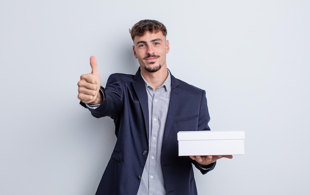 Junger gutaussehender Mann, der stolz ist und positiv mit Daumen nach oben lächelt. White-Box-Paket