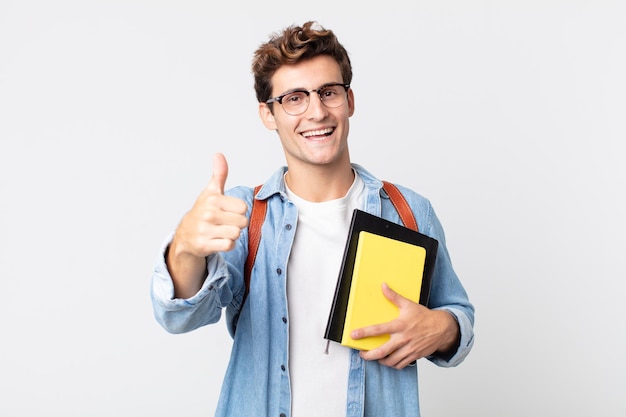 Junger gutaussehender mann, der stolz ist und positiv mit erhobenen daumen lächelt. universitätsstudentenkonzept