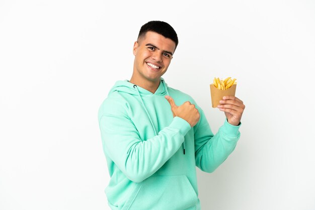 Junger gutaussehender Mann, der stolz und selbstzufrieden gebratene Chips über isoliertem weißem Hintergrund hält