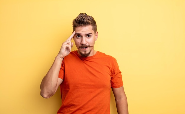 junger gutaussehender mann, der überrascht, mit offenem mund, schockiert aussieht und einen neuen gedanken, eine neue idee oder ein neues konzept verwirklicht. seltsames schnurrbartkonzept