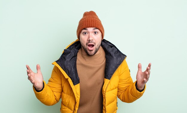 Junger gutaussehender Mann erstaunt, schockiert und erstaunt mit einer unglaublichen Überraschung. Konzept für kaltes Wetter