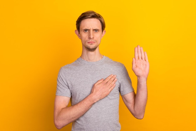 Junger gutaussehender Mann in Kleidung über isoliertem hellem Hintergrund, der die offene Handfläche der Handbrust schwört und Treueversprechen abgibt