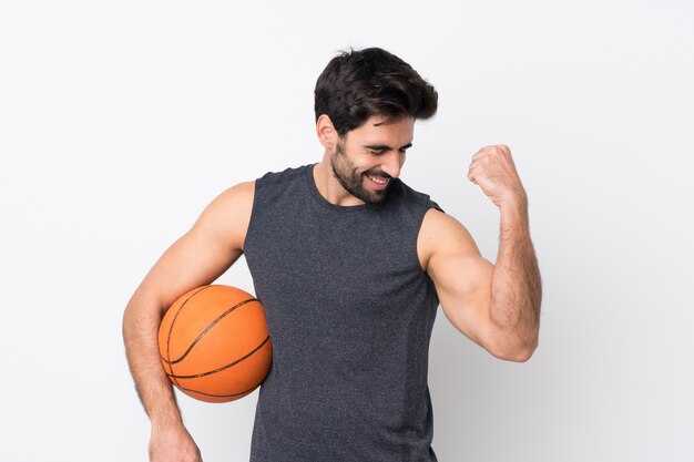 Junger gutaussehender Mann mit Bart über der lokalisierten weißen Wand, die Basketball spielt