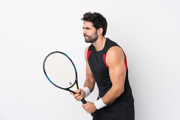 Junger gutaussehender Mann mit Bart über der lokalisierten weißen Wand, die Tennis spielt