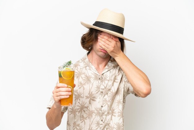 Junger gutaussehender Mann mit einem Cocktail isoliert auf weißem Hintergrund mit müdem und krankem Gesichtsausdruck
