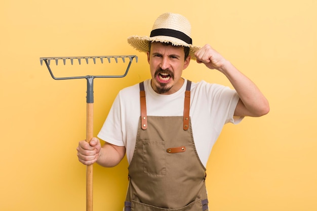 Junger gutaussehender Mann mit einem Rake Farmer-Konzept