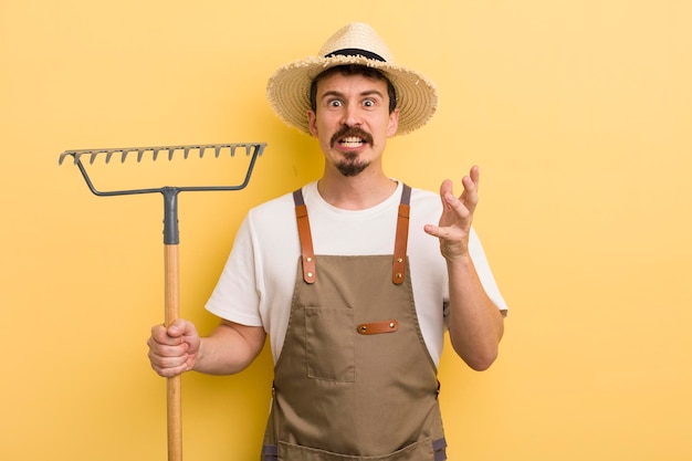 Junger gutaussehender Mann mit einem Rake Farmer-Konzept