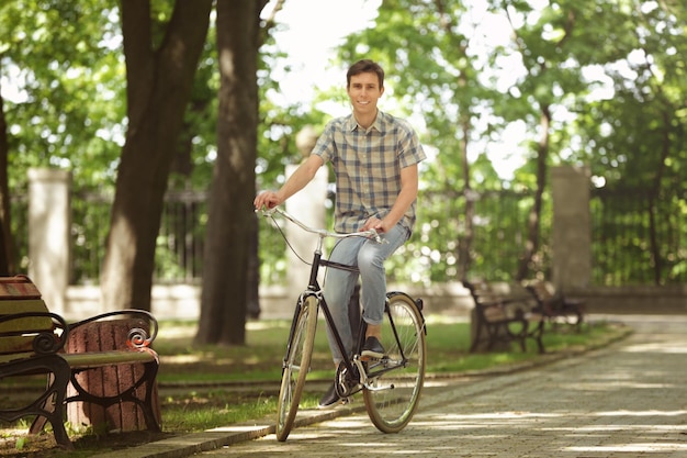 Junger gutaussehender Mann mit Fahrrad im Freien an einem sonnigen Tag