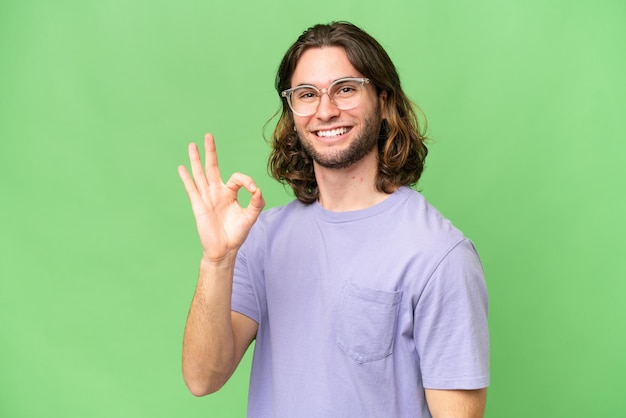 Junger gutaussehender Mann mit isoliertem Hintergrund, der mit den Fingern ein Ok-Zeichen zeigt