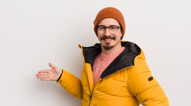 Junger gutaussehender Mann mit Mantel gegen weiße Wand