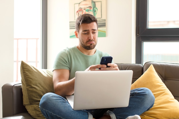 Junger gutaussehender Mann mit seinem Smartphone zu Hause