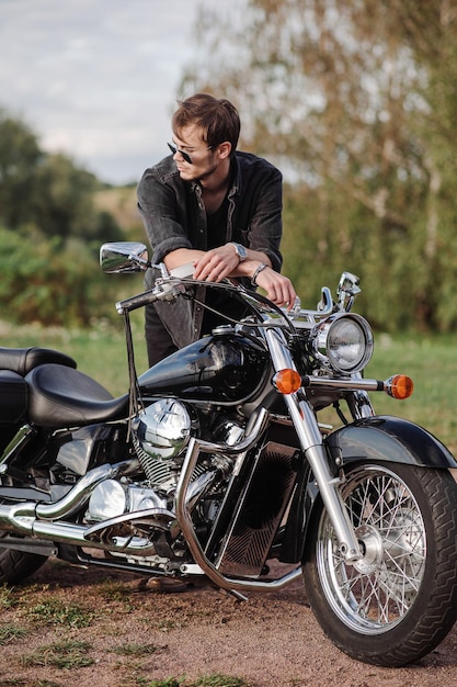 Junger gutaussehender Mann sitzt draußen auf seinem Motorrad