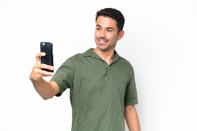 Junger gutaussehender Mann vor isoliertem weißem Hintergrund, der ein Selfie macht