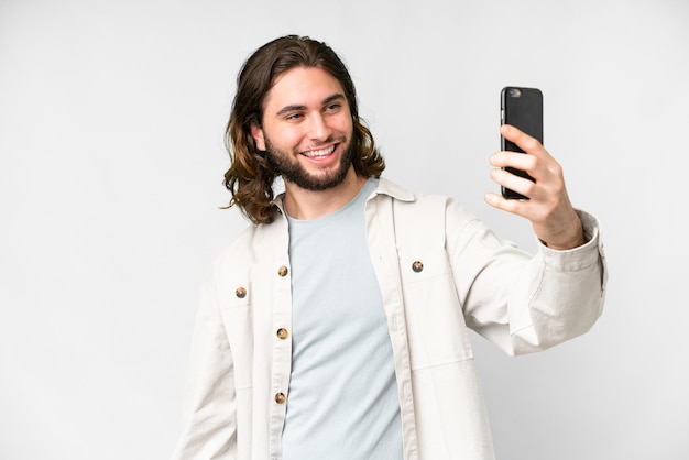 Junger gutaussehender Mann vor isoliertem weißem Hintergrund, der ein Selfie macht