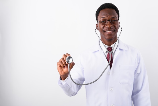 Junger gutaussehender Mannarzt, der Stethoskop gegen Weiß verwendet
