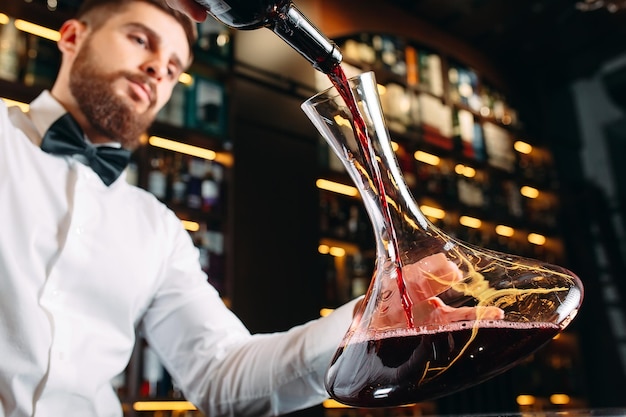 Junger gutaussehender Sommelier, der Rotwein im Keller verkostet.