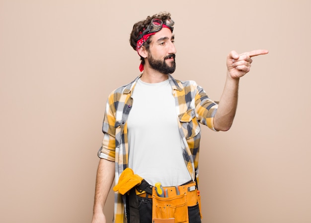 Junger Haushälterin, der sich schockiert und überrascht fühlt, ehrfürchtig zeigt und mit erstauntem Blick mit offenem Mund gegen flache Wand nach oben schaut