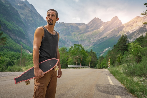 Junger Hipster, der ein cooles Longboard in der Hand hält