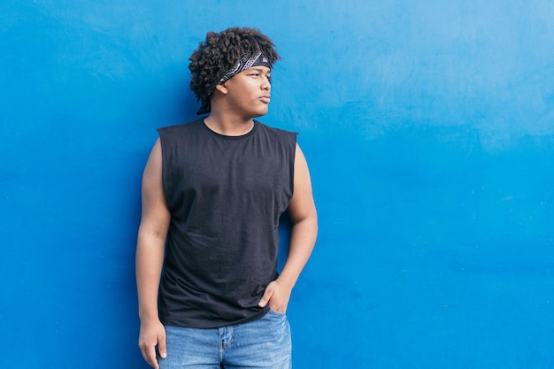 Junger hispanischer Latino-Mann, der in der Stadtstraße an der Wand steht