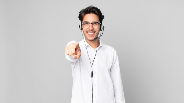 Junger hispanischer Mann, der auf die Kamera zeigt, die Sie wählt. Telemarketing-Konzept