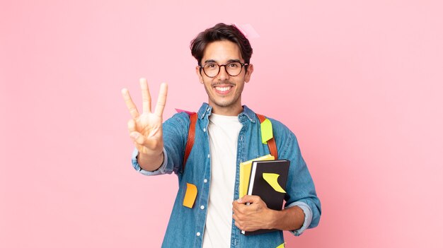 Junger hispanischer Mann, der freundlich lächelt und aussieht und Nummer drei zeigt. studentisches Konzept